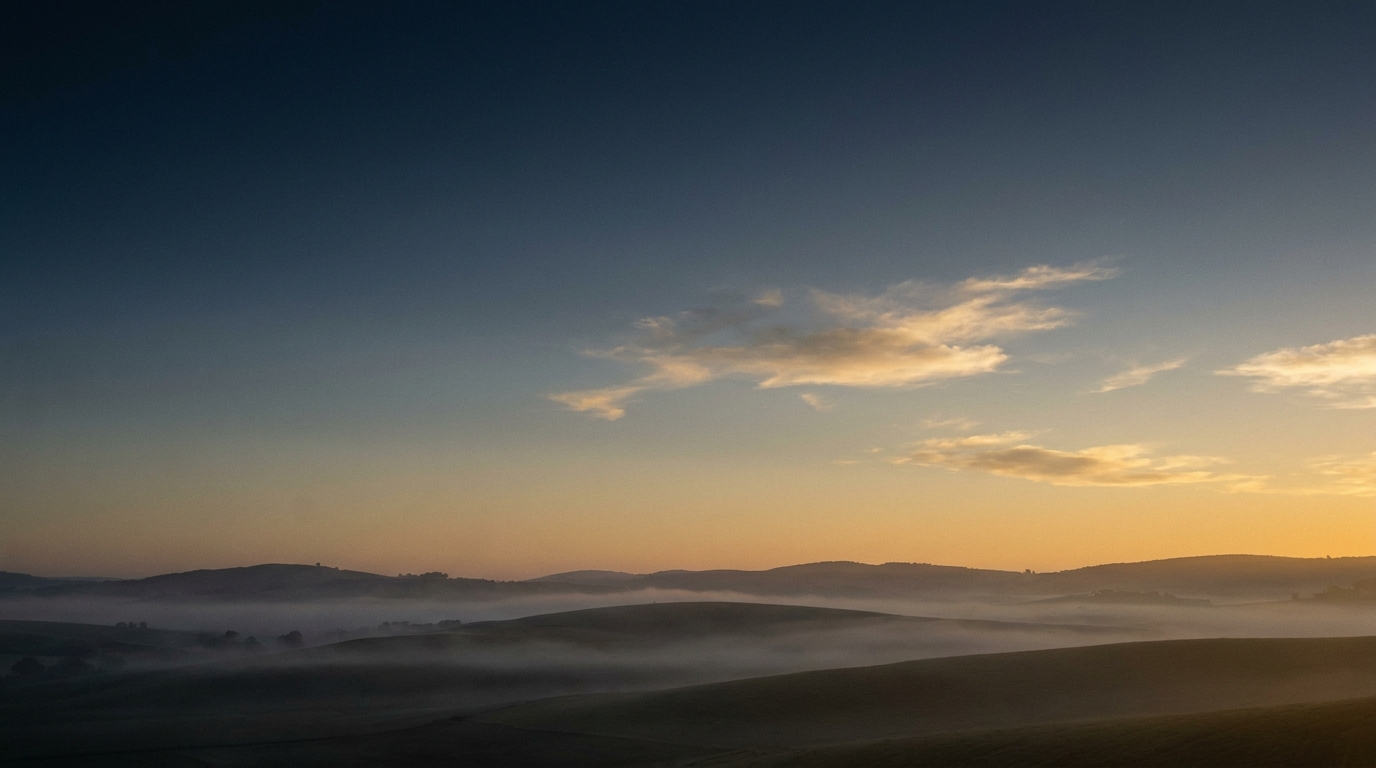 Dawn light breaking over misted rolling hills